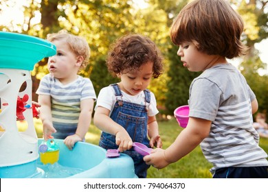 Group Of Young Children Playing With Water Table In Garden - Powered by Shutterstock