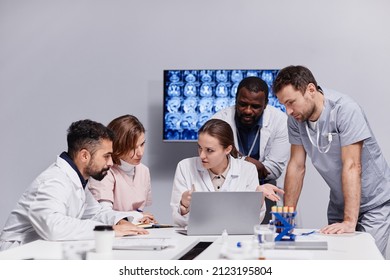 Group Of Young Colleagues Listening To Female Clinician Explanation Of Reasons For Surgical Operation During Discussion Of Patient Brain Scan