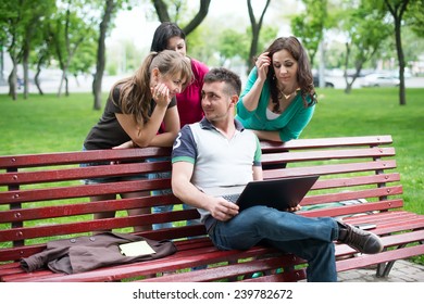Group of young college students using laptop in the park