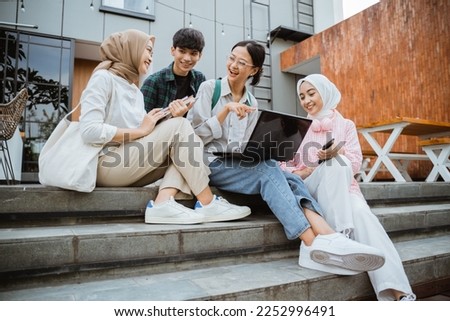 group of young college students using laptops sitting on the steps in a cafe
