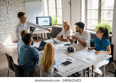 Group of young confident happy business people analyzing data during meeting in the office - Powered by Shutterstock