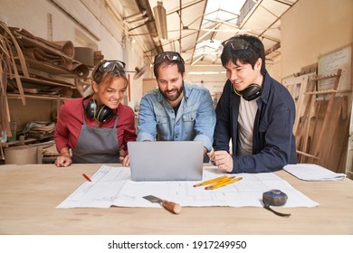 Group Of Young Craftsmen At The Laptop Computer During Planning In The Workshop