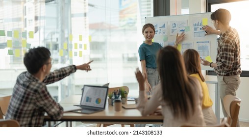 group of young creative asian people doing brainstorming meeting colleagues in board room discussing project. woman standing at white board give presentation - Powered by Shutterstock