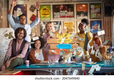 A group of young creative people are posing for a photo in a cheerful atmosphere and throwing the money around the office celebrating a success. Employees, office, work