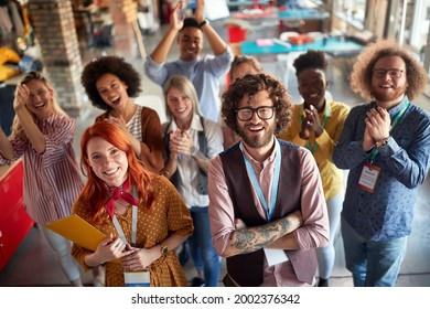 Group Of Young Creative People At Work Is Clapping And Yelling While Posing For A Photo In A Cheerfull Atmosphere In The Office Together