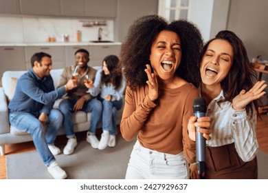 Group of young diverse friends celebrating, singing and engaging in students party activities in modern comfortable apartment, enjoy relaxing and joyful weekend time together. Selective focus - Powered by Shutterstock