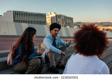 A Group Of Young Diverse Friends Are Outdoors In The City Eating Takeout Food Together.