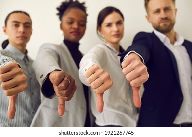 Group of young diverse people giving thumbs down, hands in closeup. Multiracial corporate HR managers saying no and refusing a person. Multiethnic business team showing dislike of bad work