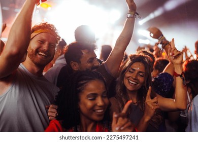 A group of young diverse people are having a great time listening and dancing to their favorite band in a concert. - Powered by Shutterstock