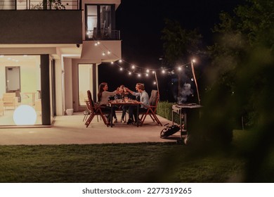 A group of young diverse people having dinner on the terrace of a modern house in the evening. Fun for friends and family. Celebration of holidays, weddings with barbecue. - Powered by Shutterstock