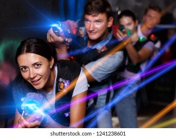 Group young emotional people with laser guns  playing laser tag  game together in dark corridor