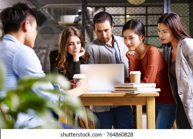 Group Of Young Entrepreneurs Asian And Caucasian Man And Woman Meeting In Office Discussing Business Using Laptop Computer.