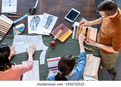 Group of young fashion designers discussing textile samples for new seasonal collection - Powered by Shutterstock