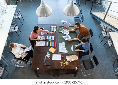 Group of young fashion designers discussing sketches and samples for new seasonal collection - Powered by Shutterstock