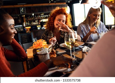 Group Of Young Female Friends Having Fun In Restaurant, Talking And Laughing While Dining At Table.