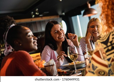 Group Of Young Female Friends Having Fun In Restaurant, Talking And Laughing While Dining At Table.