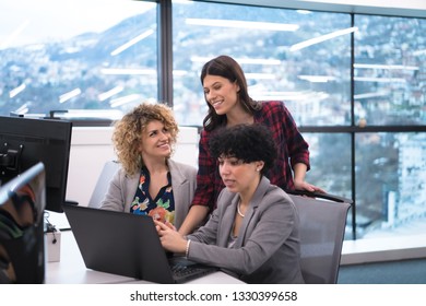 group of young female software developers using laptop computer while writing programming code at modern creative startup office