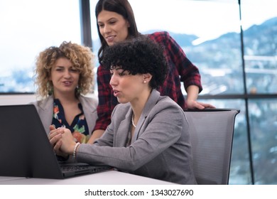 group of young female software developers using laptop computer while writing programming code at modern creative startup office