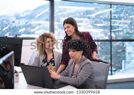 group of young female software developers using laptop computer while writing programming code at modern creative startup office