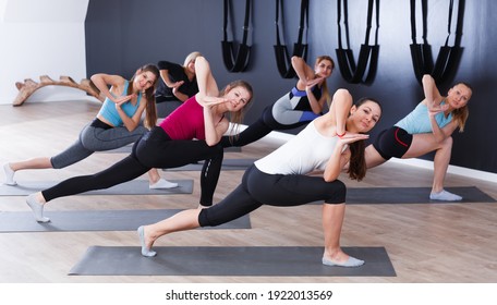 Group Of Young Females Exercising During Yoga Class At Gym