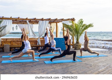 group of young females practicing yoga on the seaside during the sunrise - Powered by Shutterstock