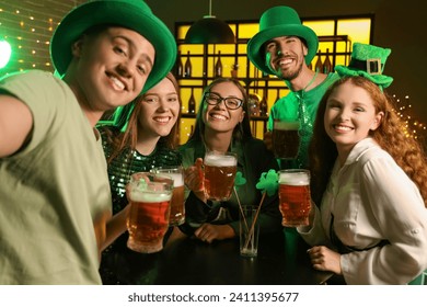 Group of young friends with beer celebrating St. Patrick's Day in pub at night - Powered by Shutterstock