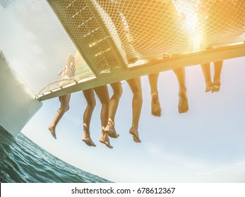 Group of young friends chilling in catamaran boat - Relaxed people making tour ocean trip - Travel, summer, friendship, tropical concept - Focus on two left men feet - Tilted horizon composition