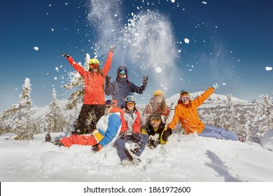 Group Of Young Friends In Colorful Clothes Are Having Fun And Posing At The Top Of Mountain. Winter Ski And Snowboarding Vacations Concept