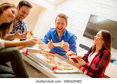 Group of young friends eating pizza at home and having fun
