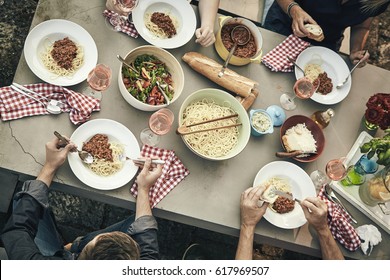 Group of young friends eating spaghetti Bolognaise with tasty fresh salads outdoors at a garden table viewed from above - Powered by Shutterstock