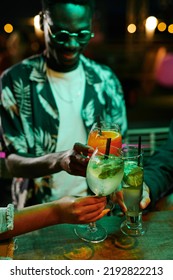 Group Of Young Friends Gathered By Bar Counter Clinking With Glasses Of Cocktails While Enjoying Rooftop Party Or Having Fun In Night Club