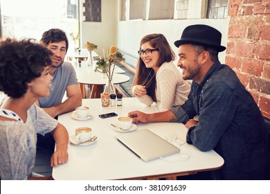 Group Of Young Friends Hanging Out At A Cafe. Young Men And Women Sitting Together And Talking In A Coffee Shop.