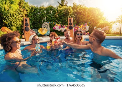 Group of young friends have fun in swimming pool, drink cocktails and toast together. - Powered by Shutterstock