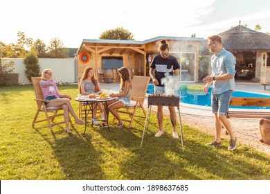 Gruppe junger Freunde mit Grillabend im Hinterhof, Grillfleisch und Spaß beim SonnenSommersonntag im Freien am Pool