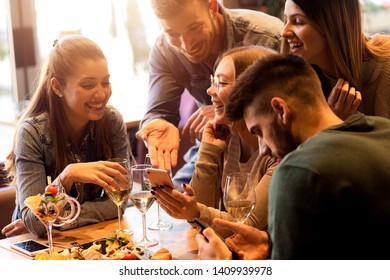 Group of young friends having fun in restaurant, talking and laughing while dining at table. - Shutterstock ID 1409939978