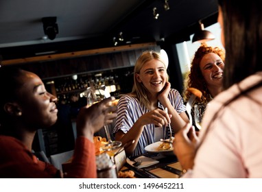 Group Of Young Friends Having Fun In Restaurant, Talking And Laughing While Dining At Table.