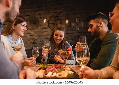 Group of young friends having fun in restaurant, talking and laughing while dining at table. - Powered by Shutterstock