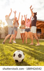 Group of young friends having fun playing football on the backyard lawn, team gathered together in a circle during time out with hands joined in the middle
