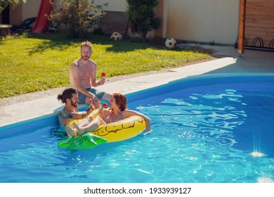 Group Of Young Friends Having Fun At Summertime Swimming Pool Party, Spending Sunny Summer Day Outdoors And Eating Watermelon Popsicles By The Pool