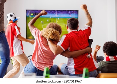 Group of young friends having fun watching football match on TV, drinking beer and cheering; football fans watching game at home celebrating after their team scoring a goal. Focus on the man in jersey - Powered by Shutterstock