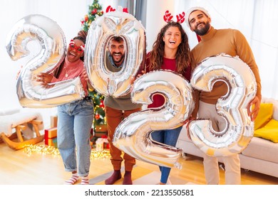 Group of young friends having fun celebrating New Year at home, holding giant balloons shaped as numbers 2023 - Powered by Shutterstock
