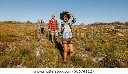 Group of young friends hiking in countryside. Multiracial young people on country walk.