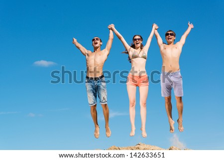 a group of young friends jumping on a background of blue sky, having fun