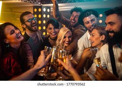 Group of young friends making a celebratory toast in a bar - Powered by Shutterstock