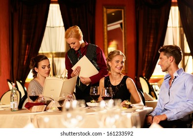 Group Of Young Friends With Menus Choosing In A Luxury Restaurant