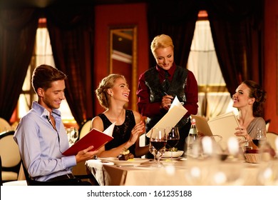 Group Of Young Friends With Menus Choosing In A Luxury Restaurant