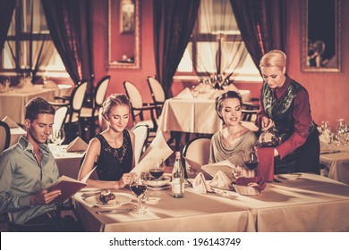 Group Of Young Friends With Menus Choosing In A Luxury Restaurant