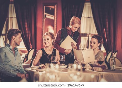 Group Of Young Friends With Menus Choosing In A Luxury Restaurant