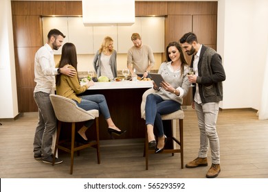 Group of young friends are in modern kitchen, talking to each other while preparing food - Powered by Shutterstock