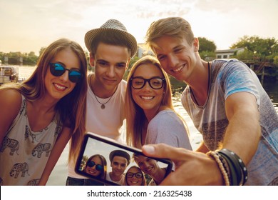 Group Of Young Friends Near River Taking Selfie Using Digital Tablet